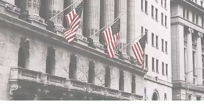 Fachada neoclásica de un edificio bursátil con banderas estadounidenses, representando el mercado de acciones